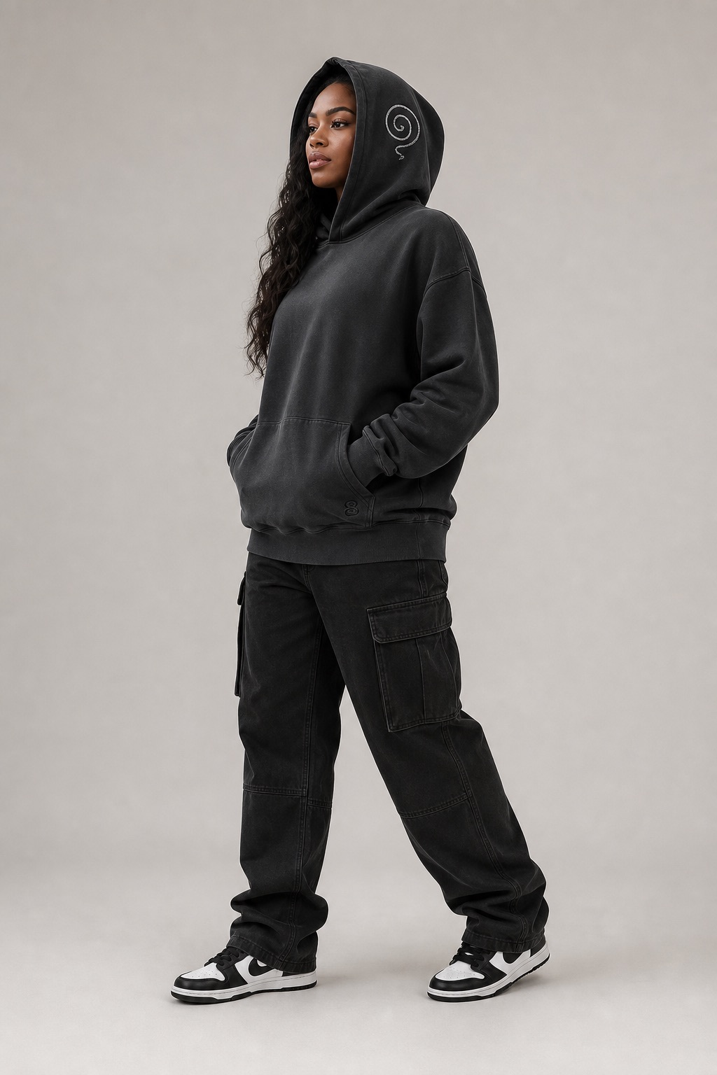 Woman in a washed-black Gratitude Collective hoodie with the spiral mark on the hood